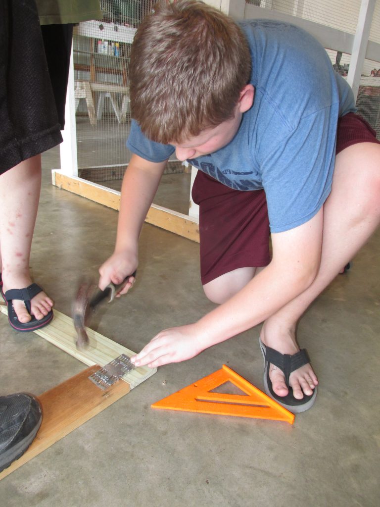 boy hammering mending plate into wood