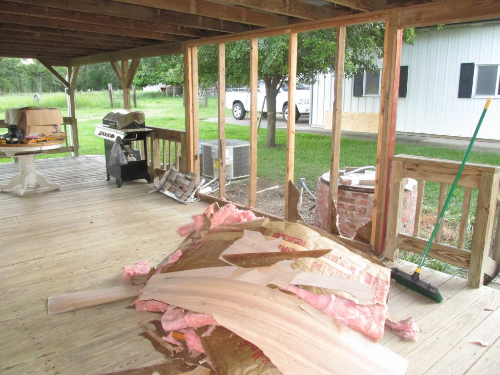 cabinets fully removed except for the studs holding the porch roof up. a pile of debris remains.